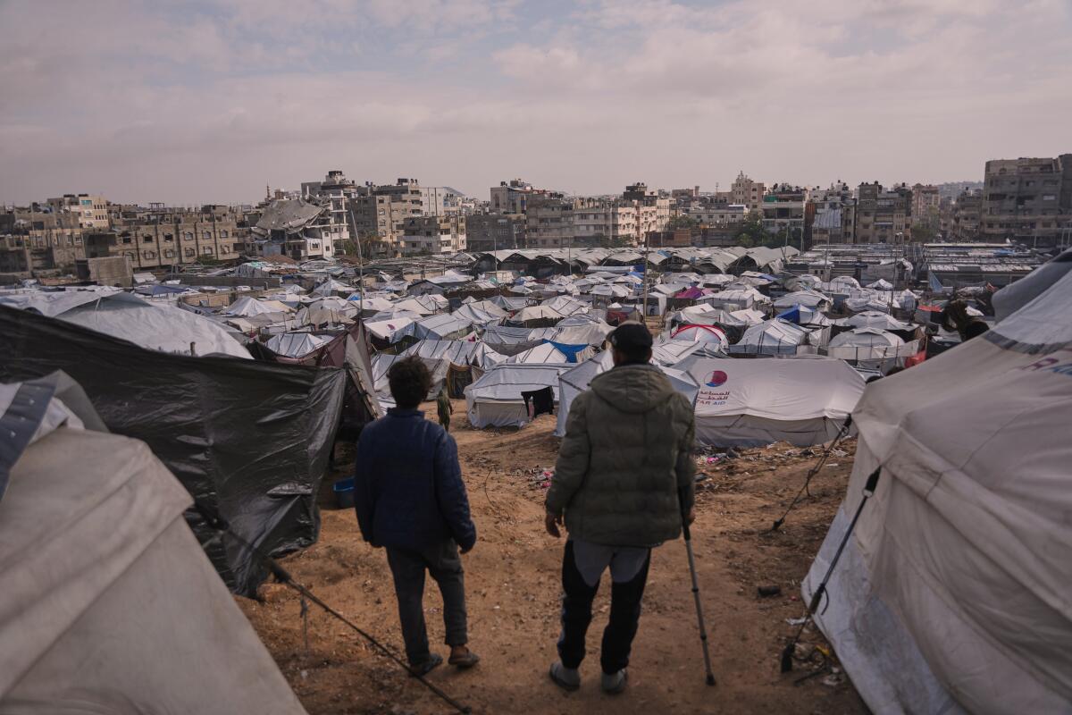 Palestinians look over makeshift tents of a camp for displaced people, set up in an area of Gaza City.