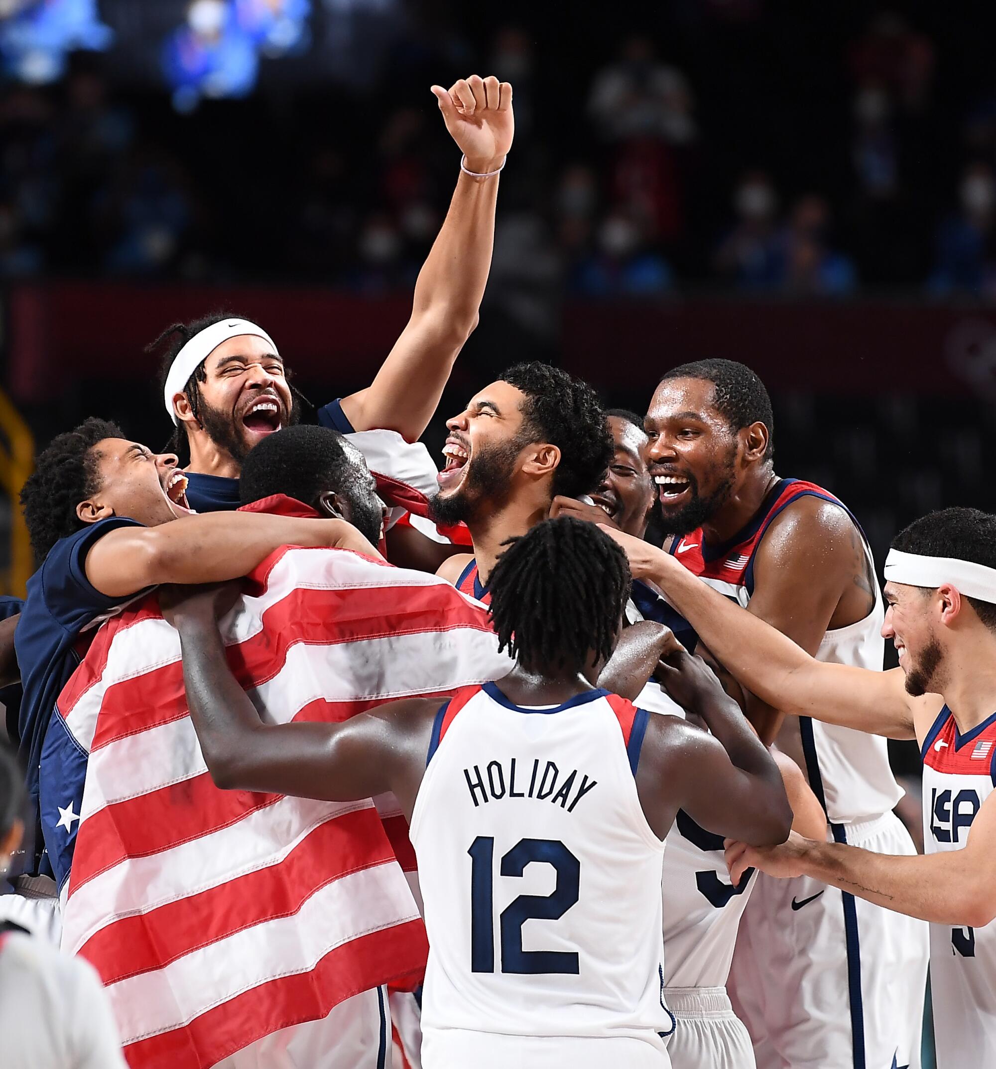 U.S. basketball players hold a flag and hug at the Tokyo Olympics