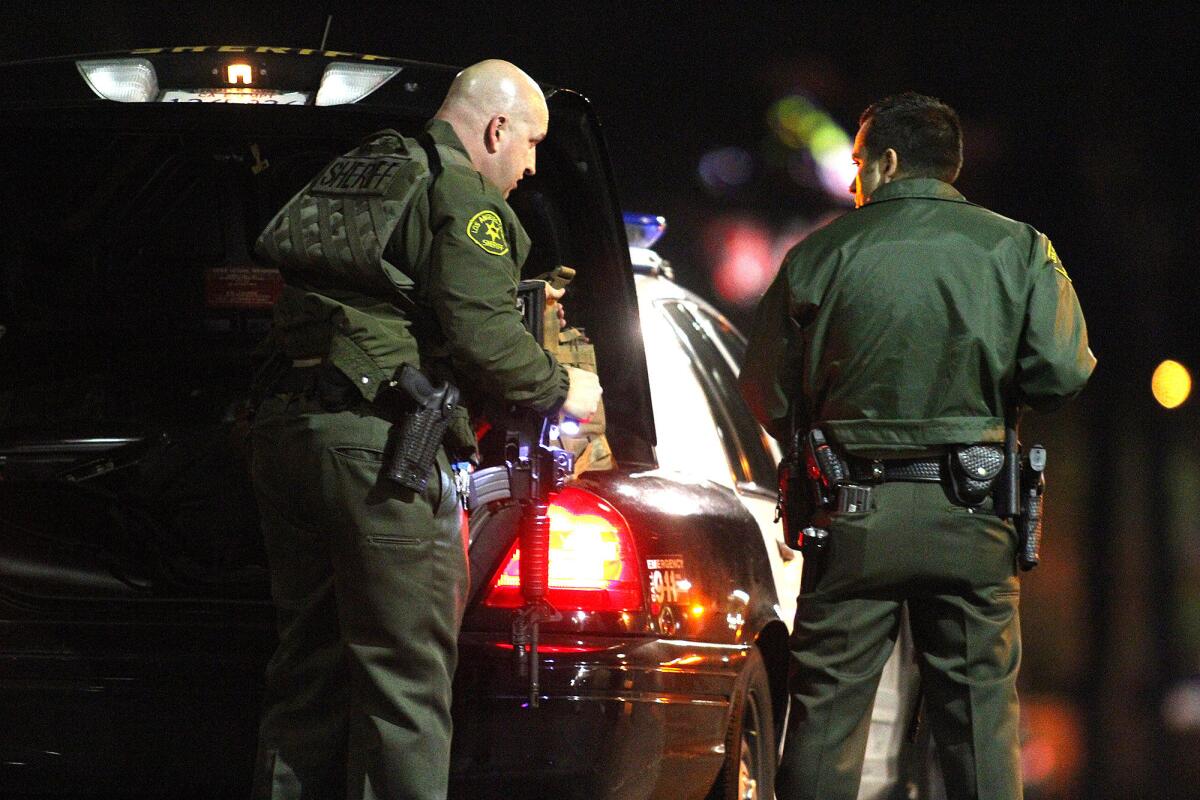 Two Los Angeles County Sheriff's deputies gear up to approach a suspect in their vehicle in La Crescenta where a man barricaded himself in a Verizon store on Friday, November 29, 2013.