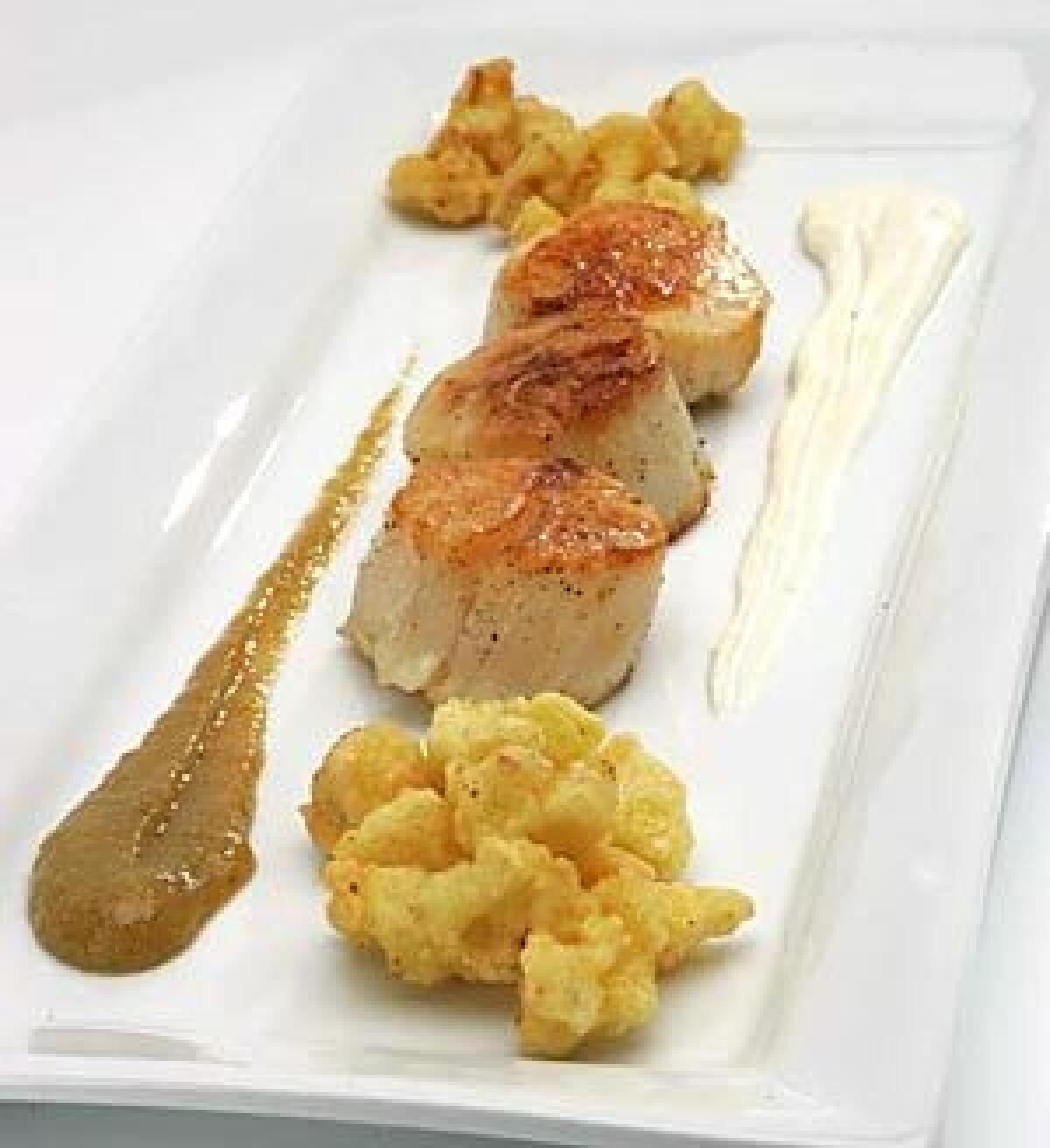 A SOPHISTICATED SIDE: Cauliflower beignets set off sauteed sea scallops and golden raisin puree spiked with three kinds of ground peppercorns.