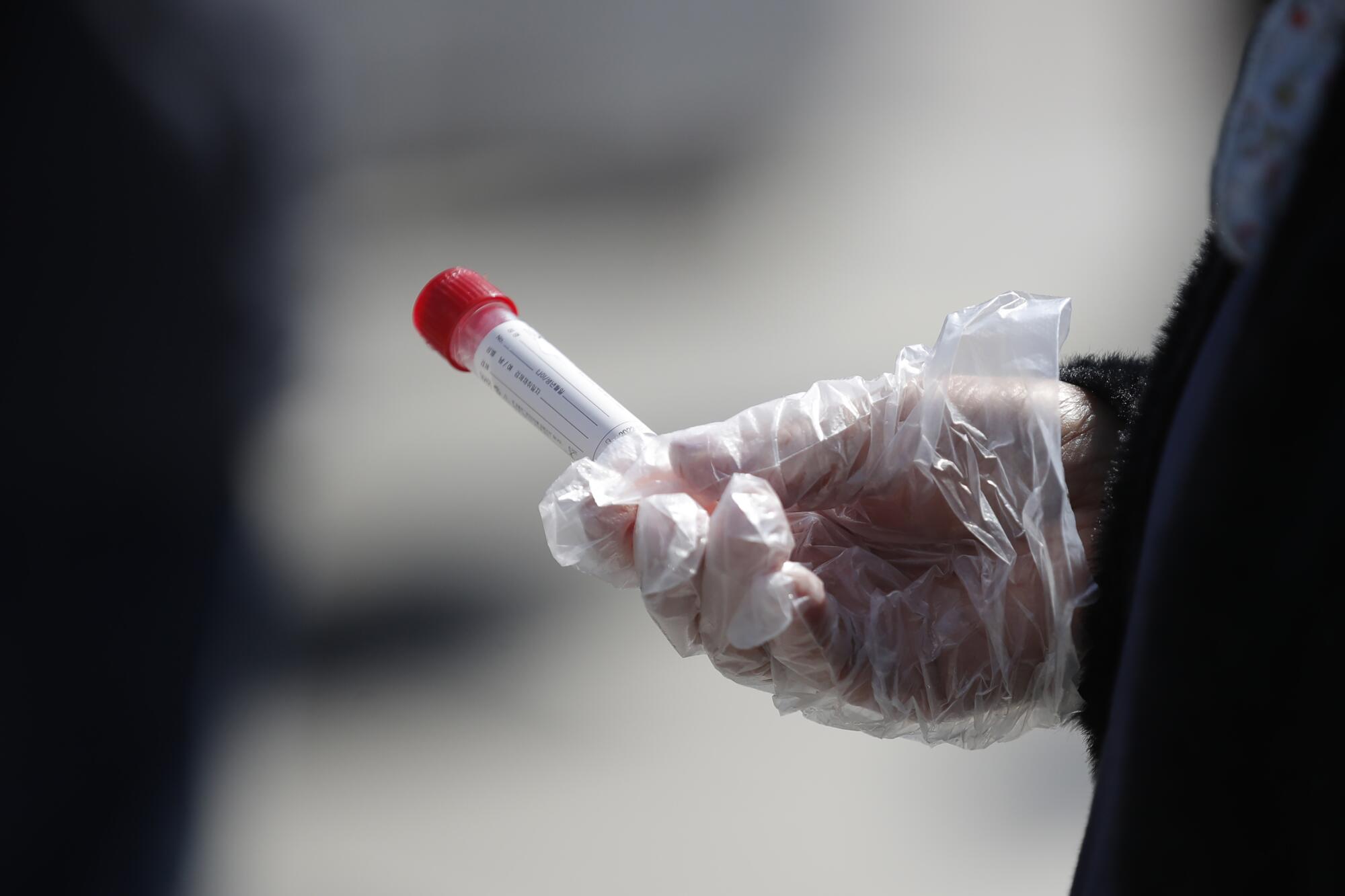 A gloved hand with a vial.