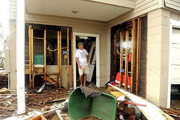 A local resident looks at damage and debris around his house in a flooded area of Galveston .