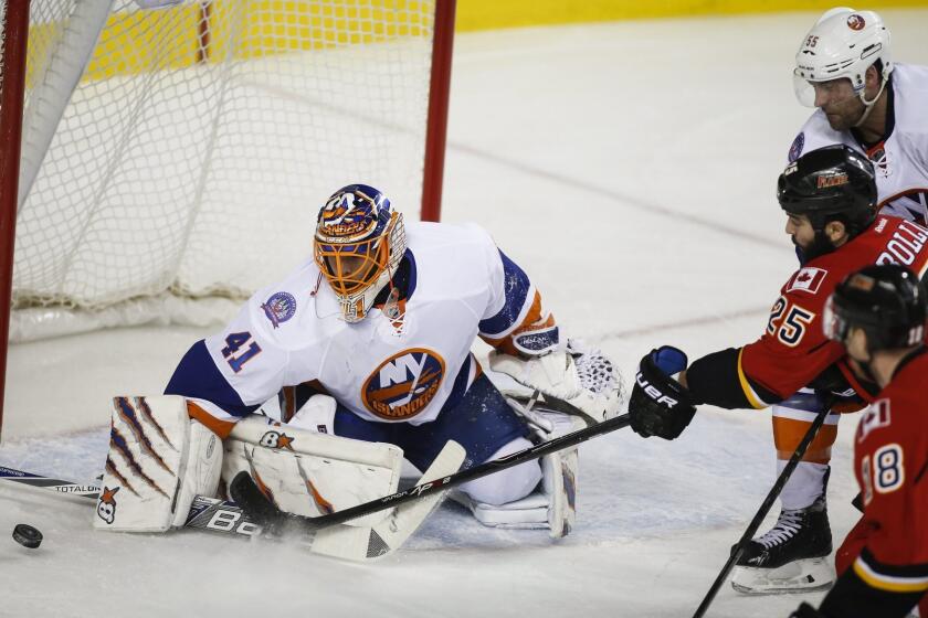 New York Islanders goalie Jaroslav Halak, left, blocks the net as Calgary's Brandon Bollig chases the puck on Jan. 2.