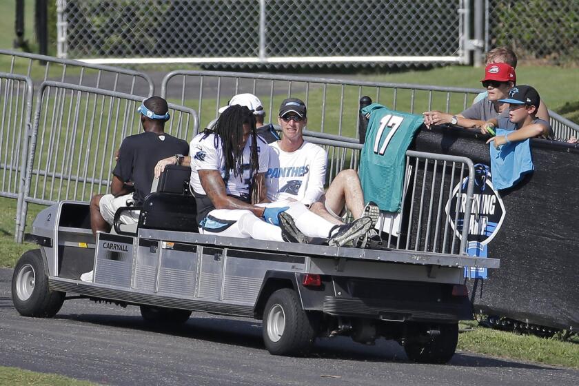 Panthers wide receiver Kelvin Benjamin holds his left knee as he is carted off the field after tearing a knee ligament during a joint practice with the Dolphins during training camp.