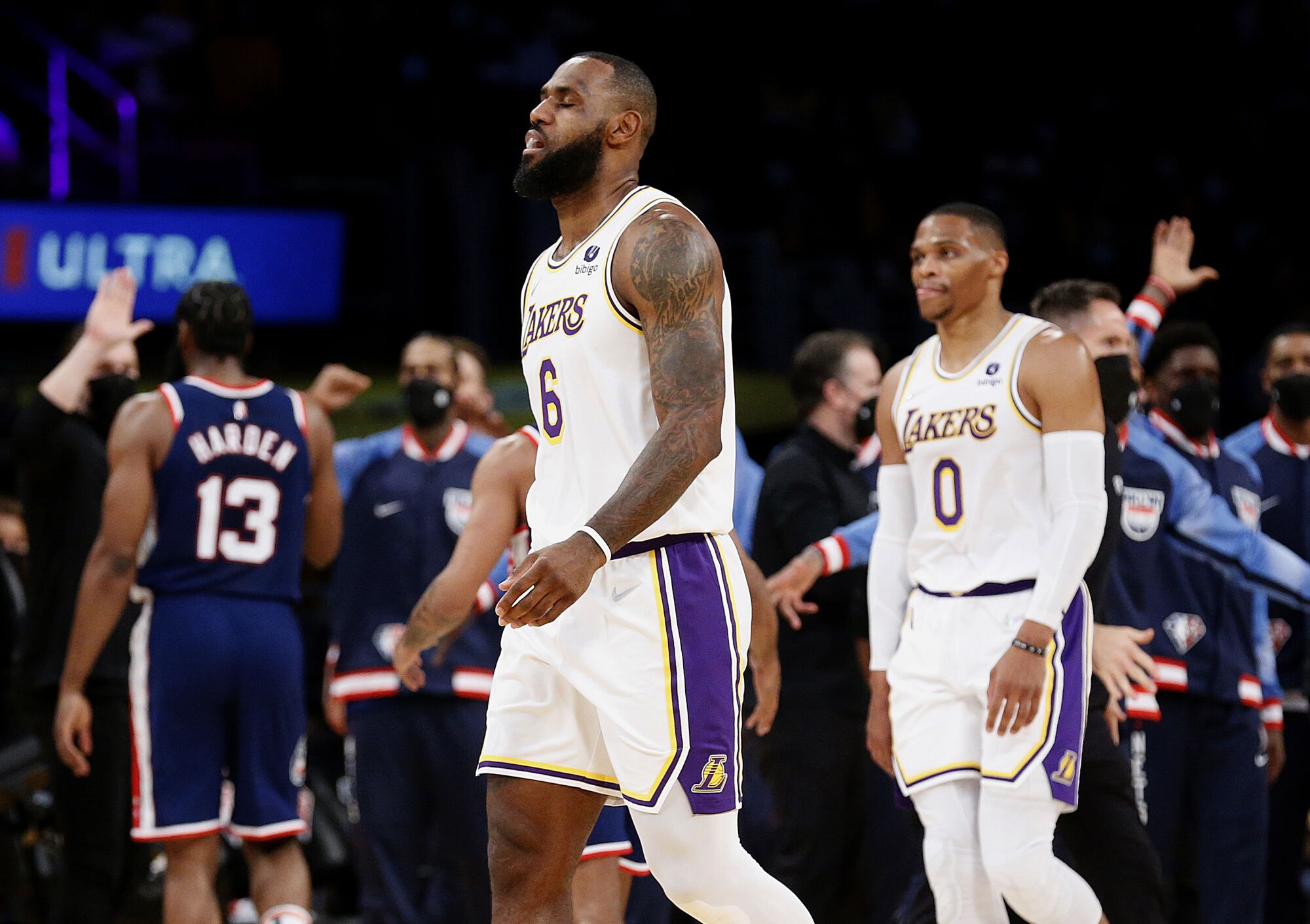 Lakers forward LeBron James, center, and guard Russell Westbrook, right, walk toward the bench.