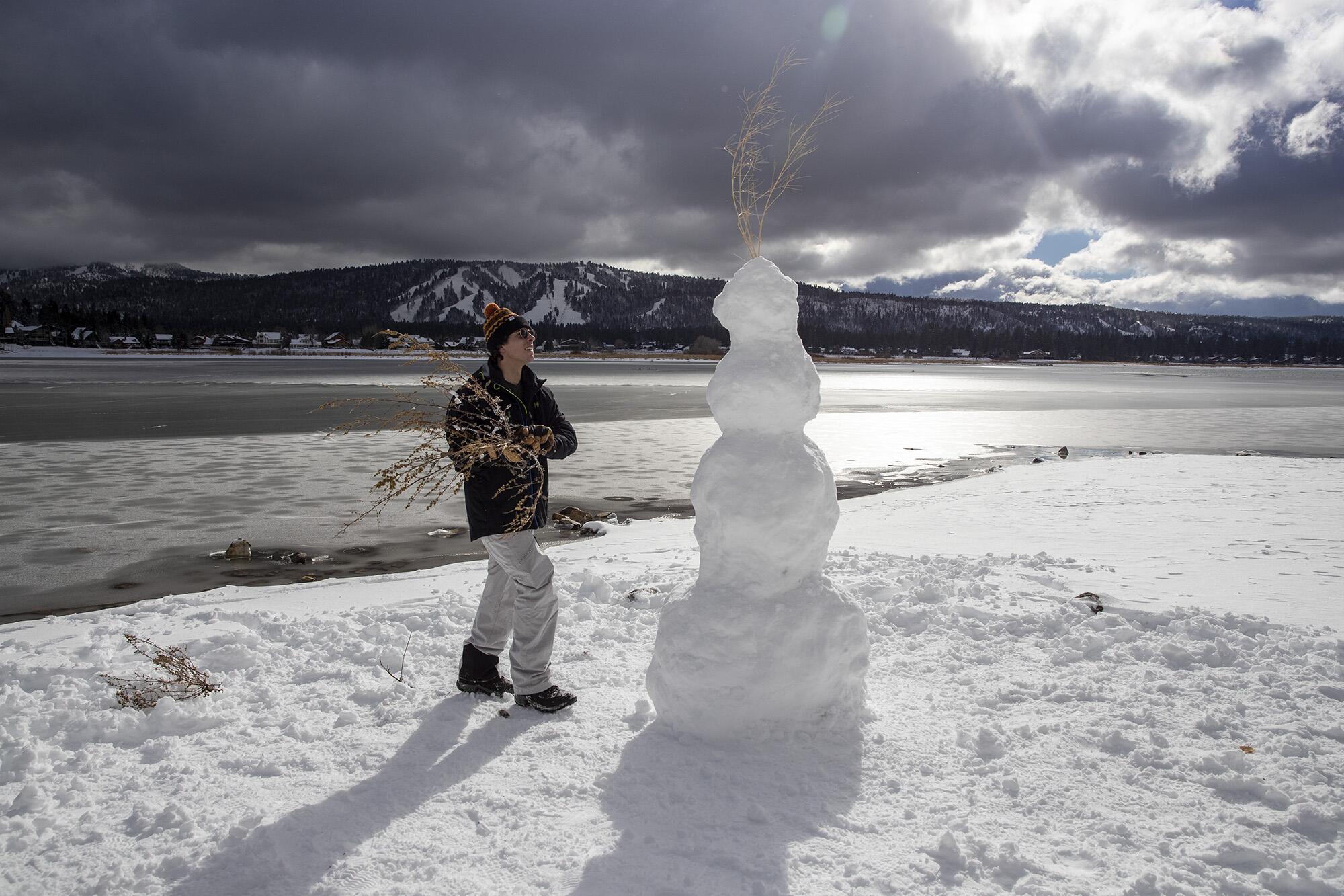 Moorpark resident Matteo Jackson, 21, puts the finishing touches on a snowman on the beach Tuesday in Big Bear Lake.