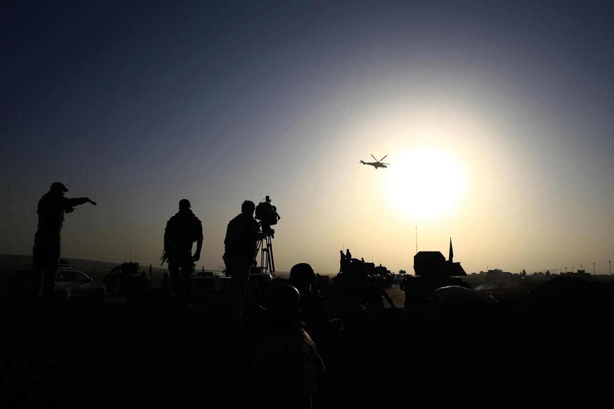 An Iraqi military helicopter flies over the front line near Bartella, Iraq, on Oct 20.