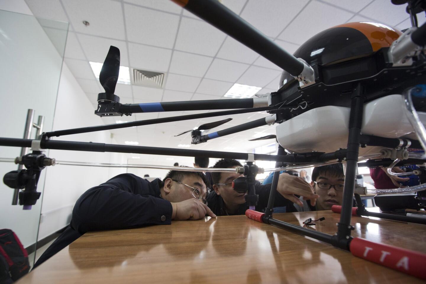 In this Oct. 17, 2015 photo, students take a close look at a drone during a theory class at a school run by TT Aviation Technology in Beijing.