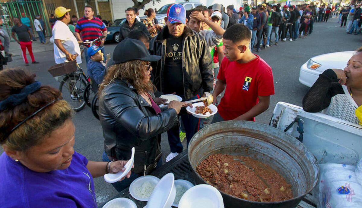 Cientos de migrantes reciben comida gratis en la 'Unidad Deportiva Benito Juárez', en Tijuana, Mexico.