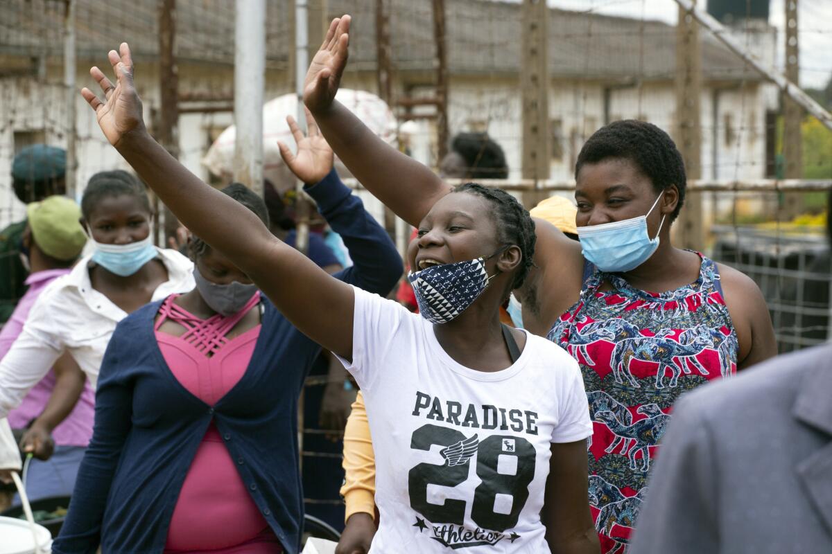 Female prsioners wave goodbye to their fellow inmates following their release from Chikurubi prison on the outskirts of Harare, Saturday, April 17, 2021. Zimbabwe began the release of about 3,000 prisoners under a presidential amnesty aimed at easing congestion and minimizing the threat of COVID-19 across the country's overcrowded jails. (AP Photo/Tsvangirayi Mukwazhi)