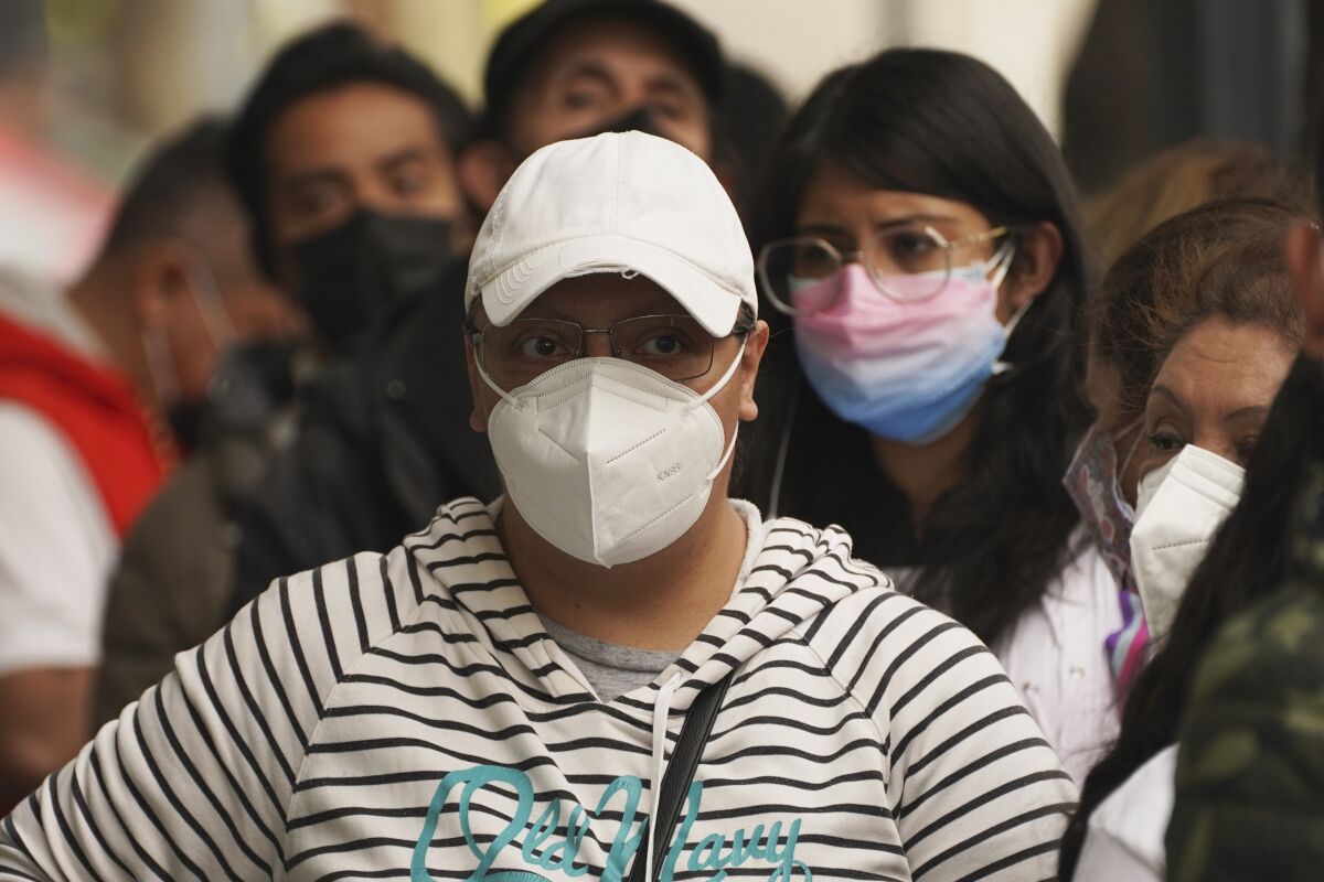 People wait outside a pharmacy to get tested for COVID-19.