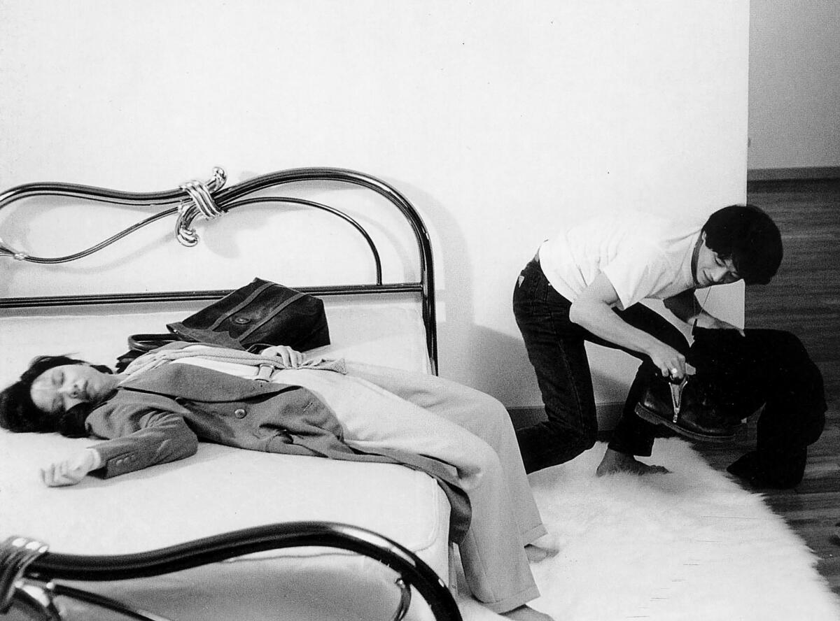 A woman lying on a bed while a man watches her