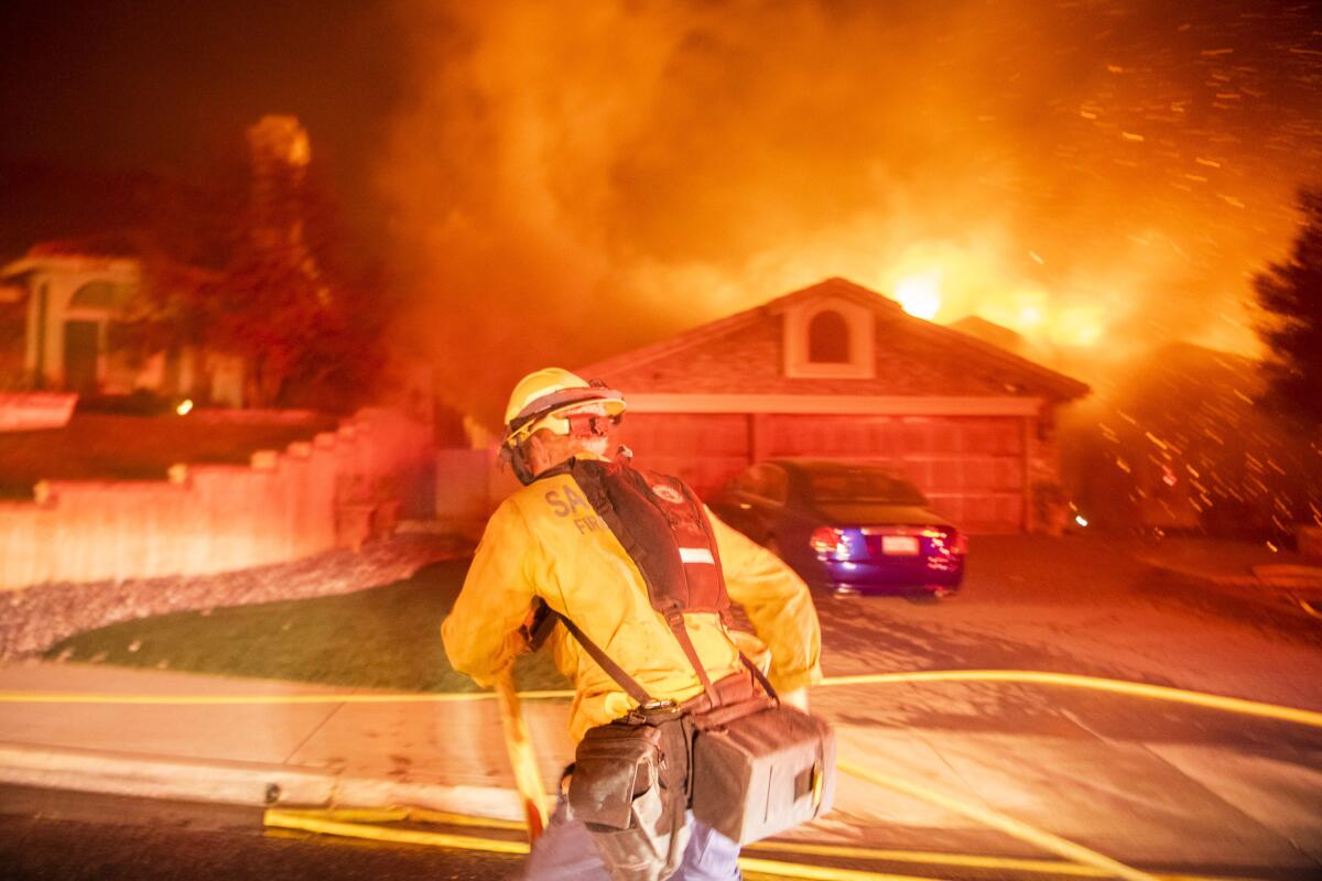 A firefighter pulls a hose to keep embers from a burning house from spreading in Oak Park on Nov. 8.