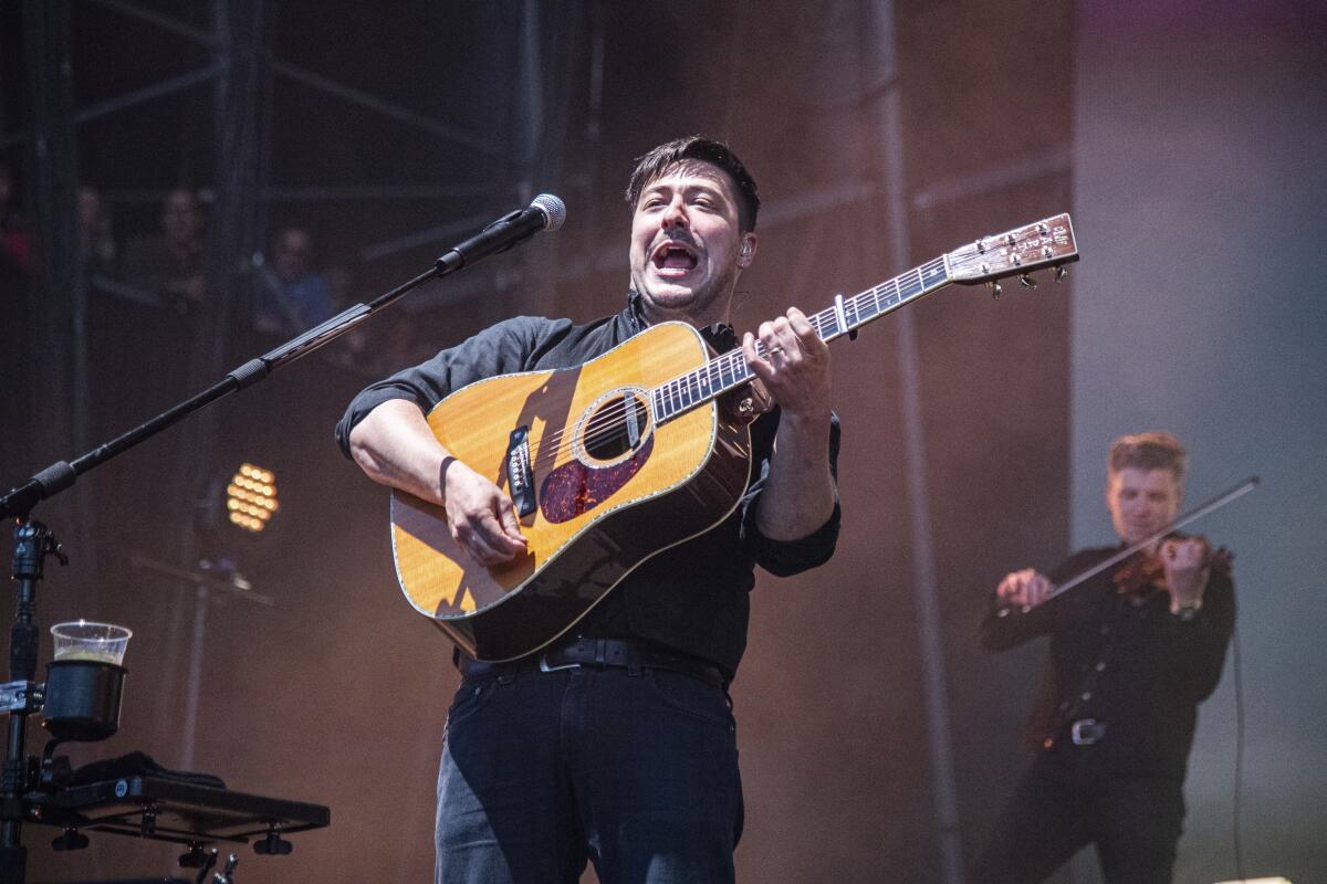 A man playing acoustic guitar on stage.