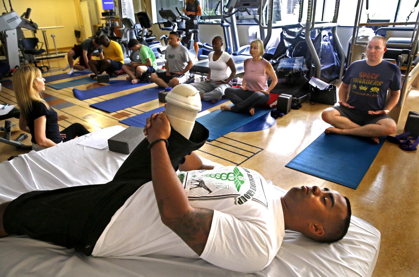 U.S. Marine Lance Cpl. Darryl Charles, 22, participates in a yoga class at the Naval Medical Center in San Diego, CA on June 10. He lost his right leg above the knee after he stepped on an IED in Afghanistan in October 2011. Other veterans with PTSD or traumatic brain injuries sit on the floor as instructor Barbara Lyon conducts the one-hour class designed to calm the mind, increase flexibility and improve physical strength.