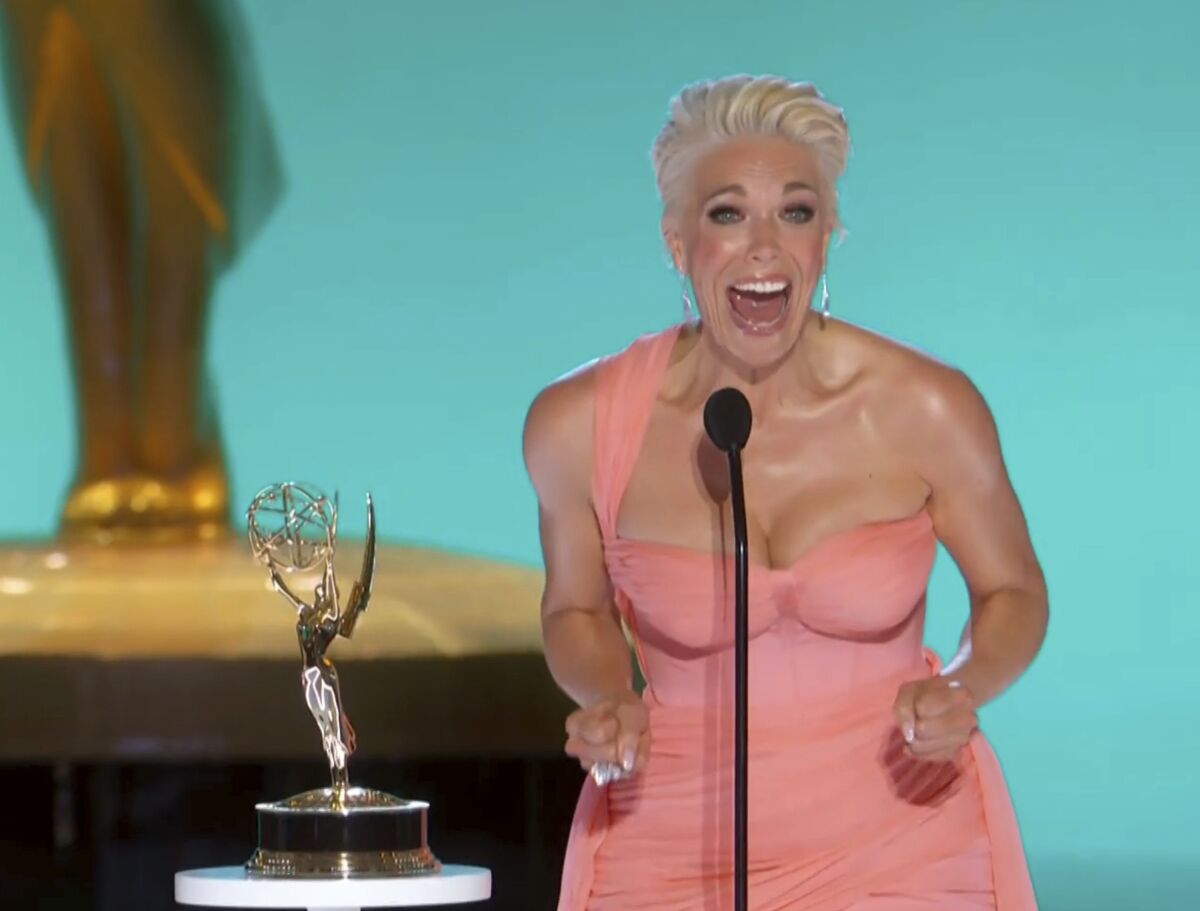 A woman in a pink dress screams happily behind a microphone