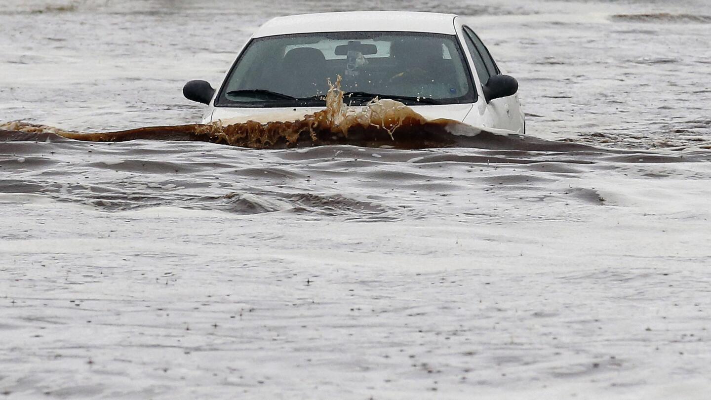 A driver tries to navigate a flooded street as heavy rains pour down Monday in Phoenix.