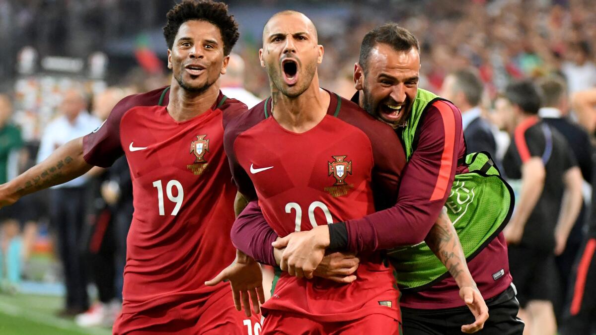 Portugal's Ricardo Quaresma (20) is swarmed by teammates Eliseu (19) and Eduardo after delivering the winning penalty kick against Poland on Thursday.
