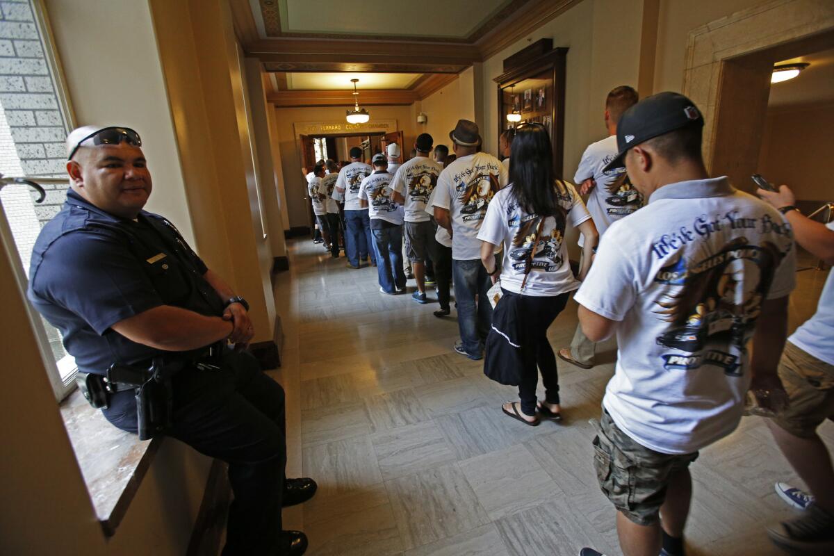 Officer Luis Ortega, left, watches as LAPD officers head to the City Council chamber as the Los Angeles Police Protective League, the union that represents 9,900 rank-and-file officers, rally and attend the council meeting in Los Angeles to call for a "fair and equitable contract."