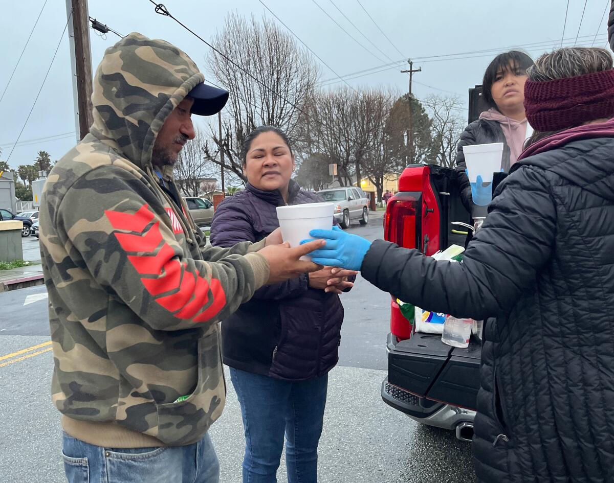 People hand a foam container of soup to a man.