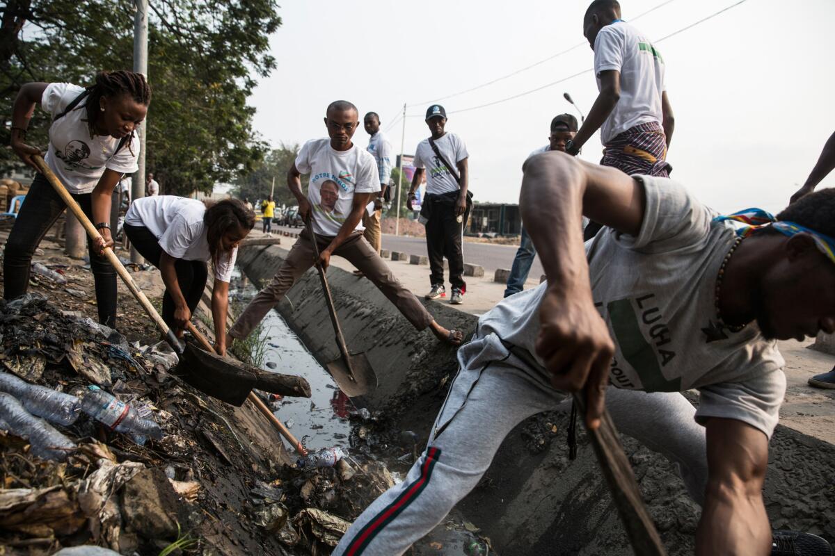 Members of the pro-democracy youth movement Lutte Pour le Changement, or LUCHA, clean up garbage during one of their public actions in Kinshasa, Congo, on Aug. 18, 2018. Eunice Etaka, left, is a law student and LUCHA member.