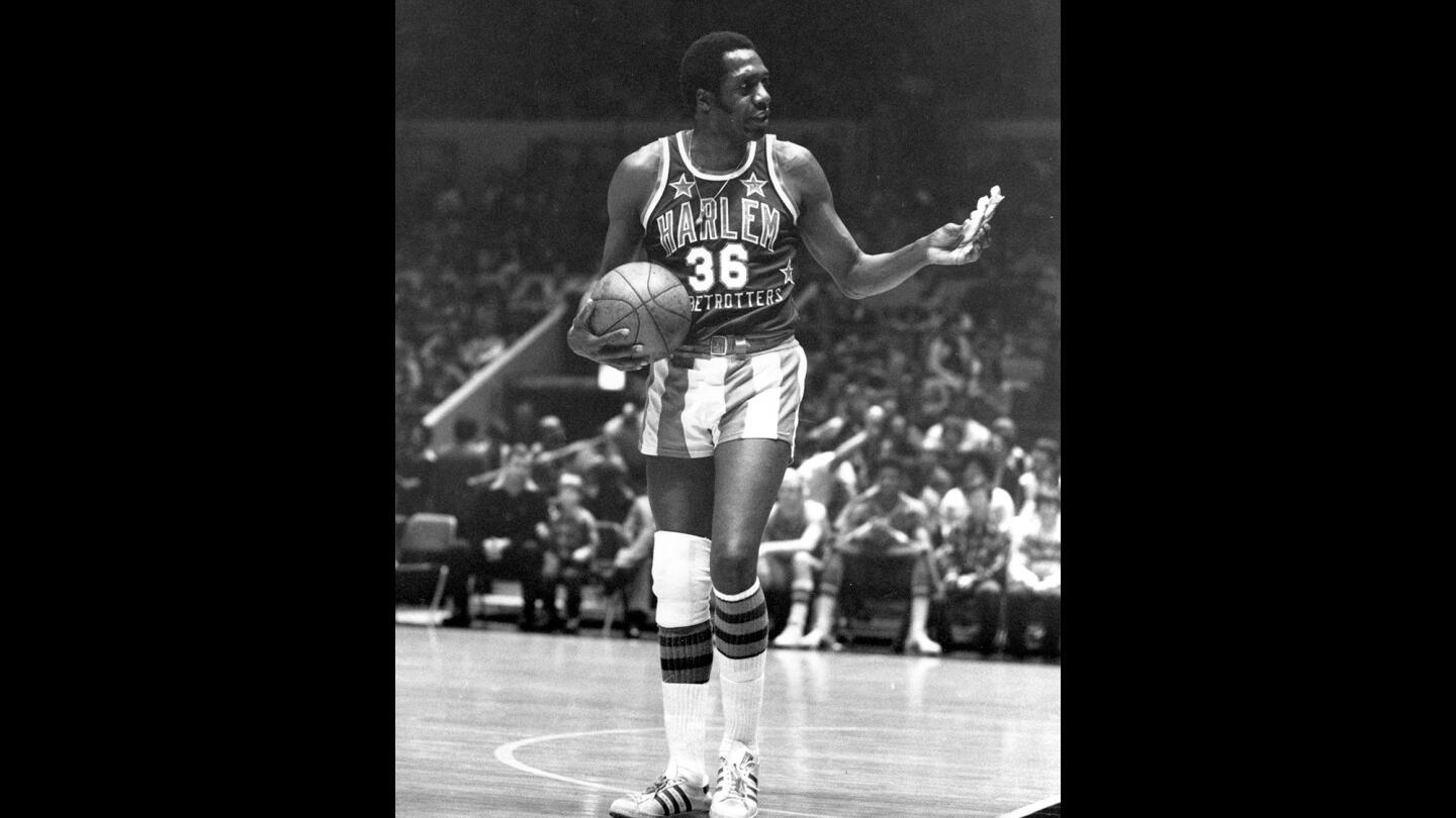 In this photo from Feb. 18, 1978, Meadowlark Lemon of the Harlem Globetrotters offers a pretzel to a referee during a game at New York's Madison Square Garden. Lemon, known as the "Clown Prince of Basketball," has died in Scottsdale, Ariz., at the age of 83.