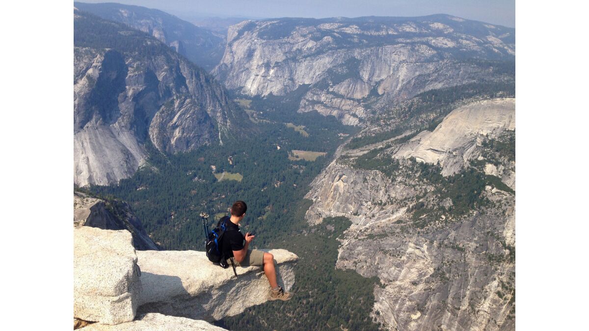 A hiker sits on a rock out-cropping on the top of Half Dome inside Yosemite National Park. The National Park Service announced via their Facebook page that due to lingering snow, the installation of the Half Dome cables will be delayed this year until at least June 2.