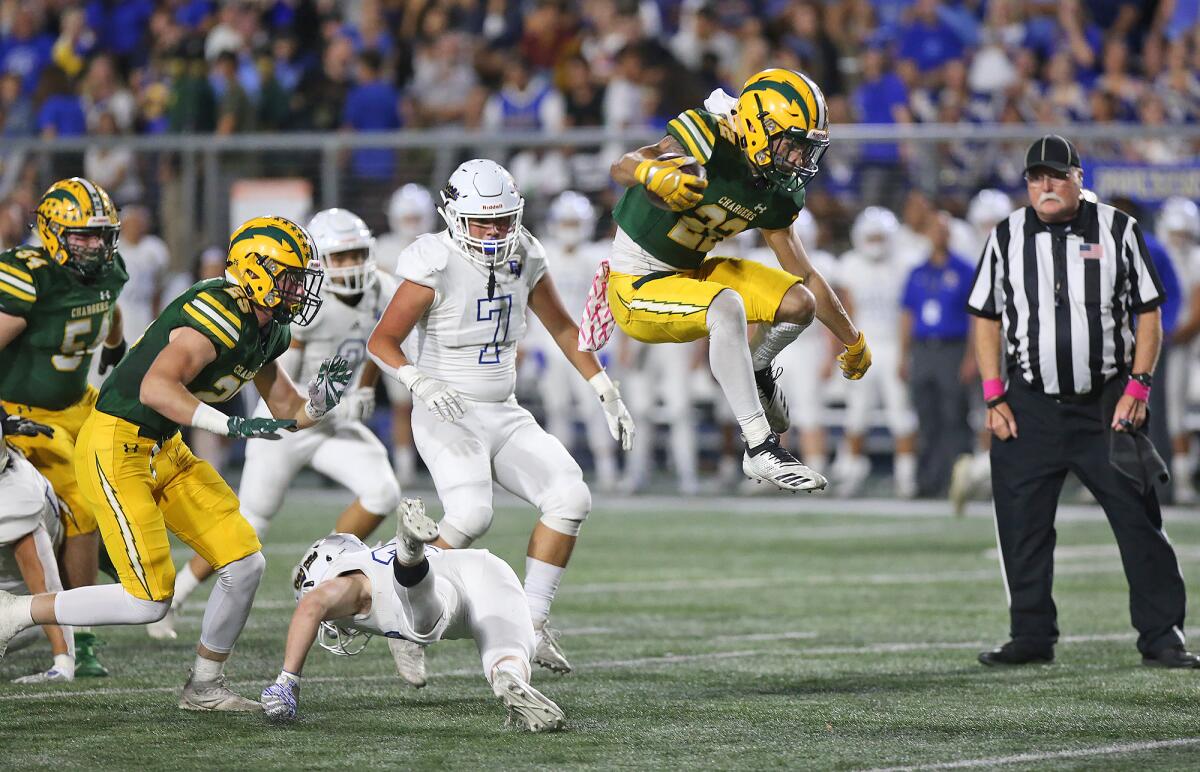 Edison's Tanner Nelson leaps over Fountain Valley's Justin Curti en route to a 32-yard touchdown run in the first quarter of the Battle for the Bell rivalry game at Orange Coast College on Friday.