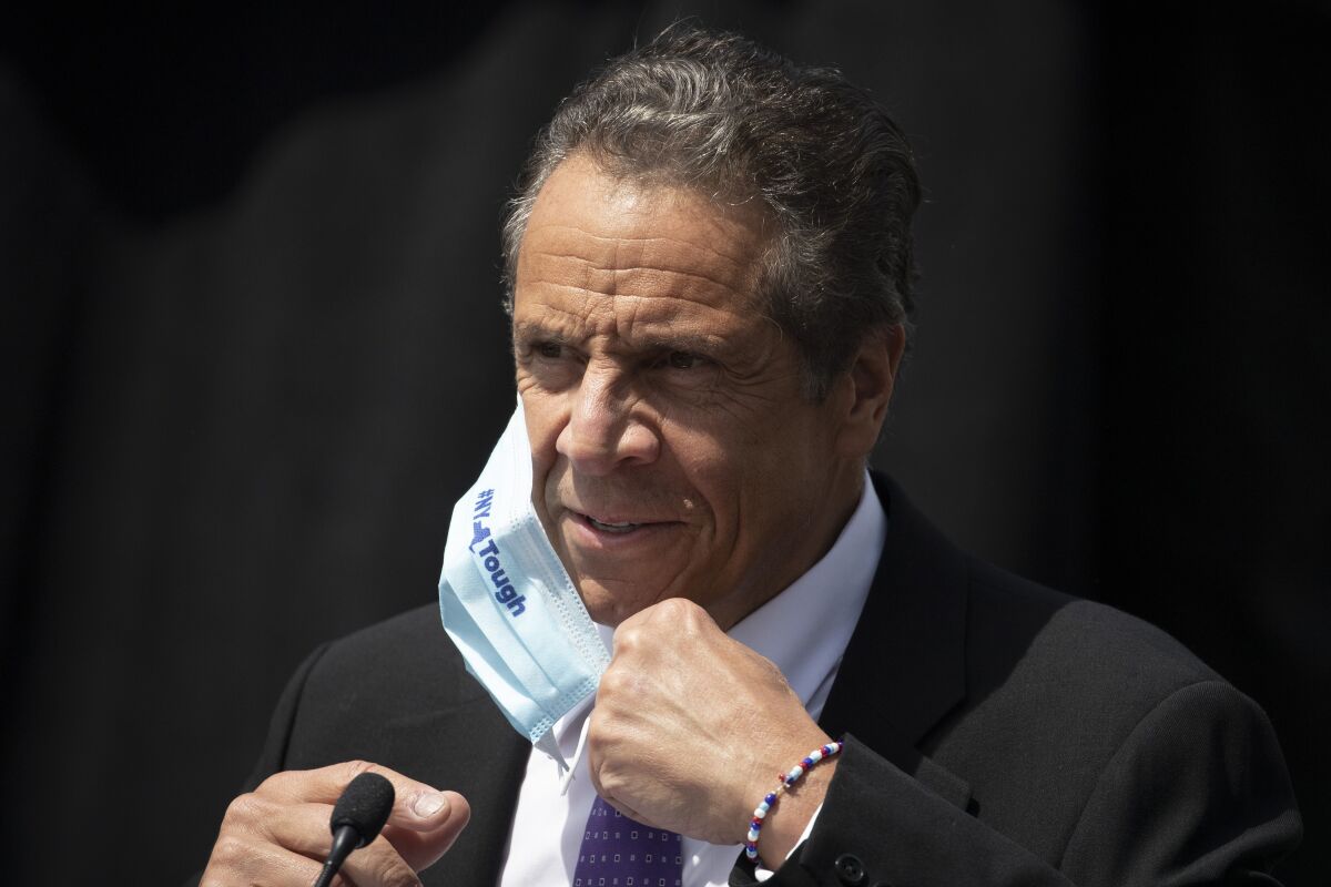 New York Gov. Andrew Cuomo pulling up a face mask. 