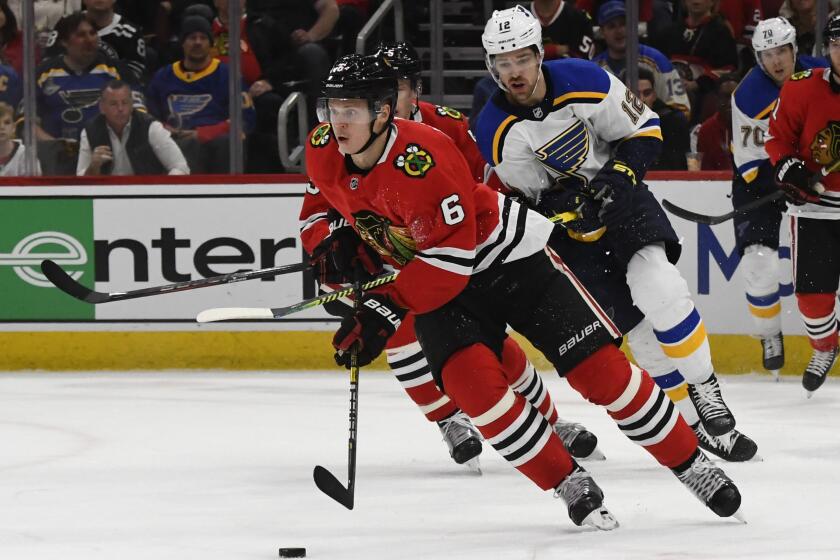 Chicago Blackhawks defenseman Olli Maatta (6) moves the puck away from St. Louis Blues left wing Zach Sanford (12) during the first period of an NHL hockey game between the Chicago Blackhawks and the St. Louis Blues on Sunday March 8, 2020, in Chicago. (AP Photo/Matt Marton)