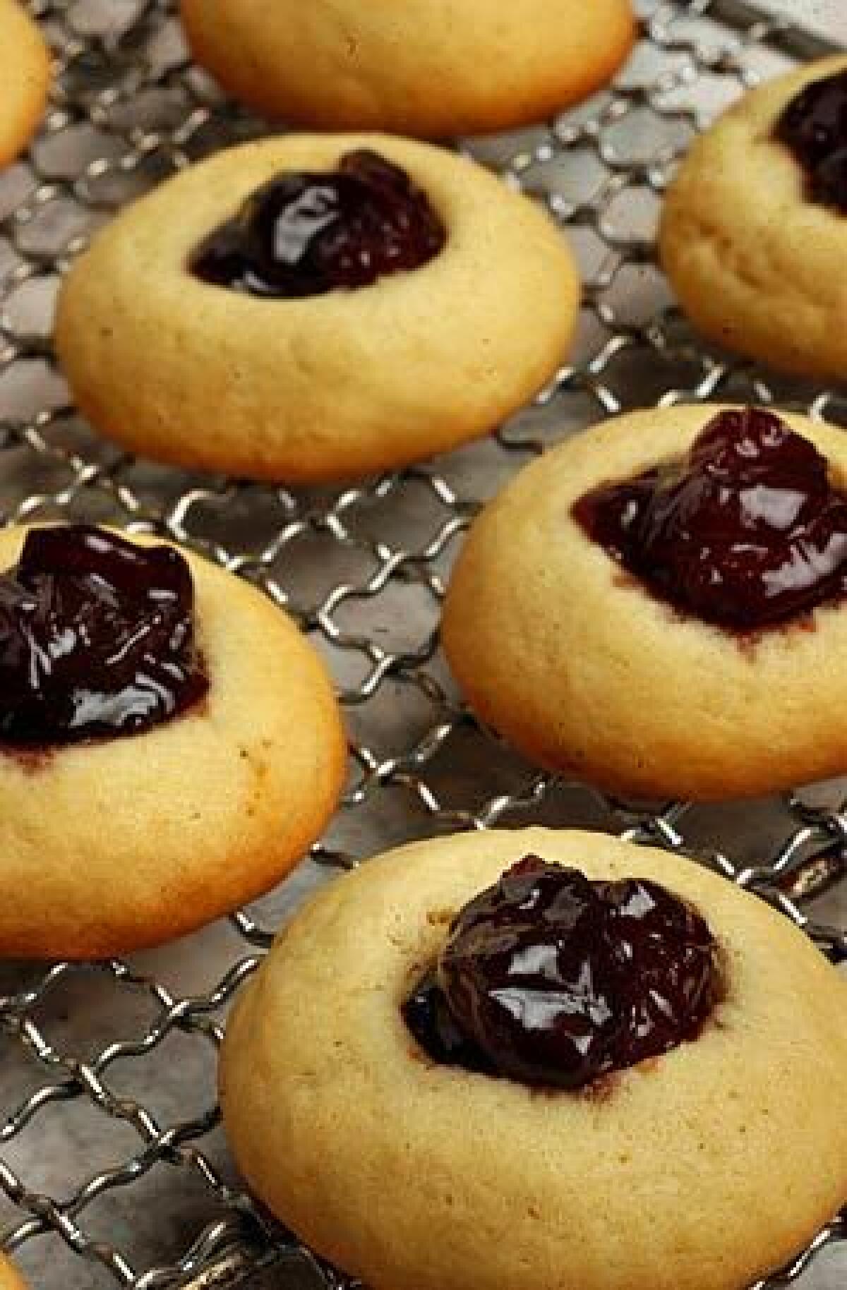 Cherry preserves are spooned into soft, golden thumbprint cookies.