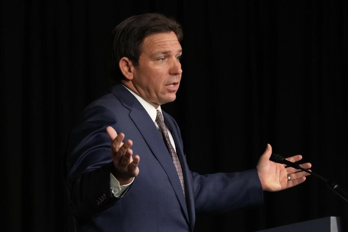 Florida Gov. Ron DeSantis speaks and holds his hands out, palms up.