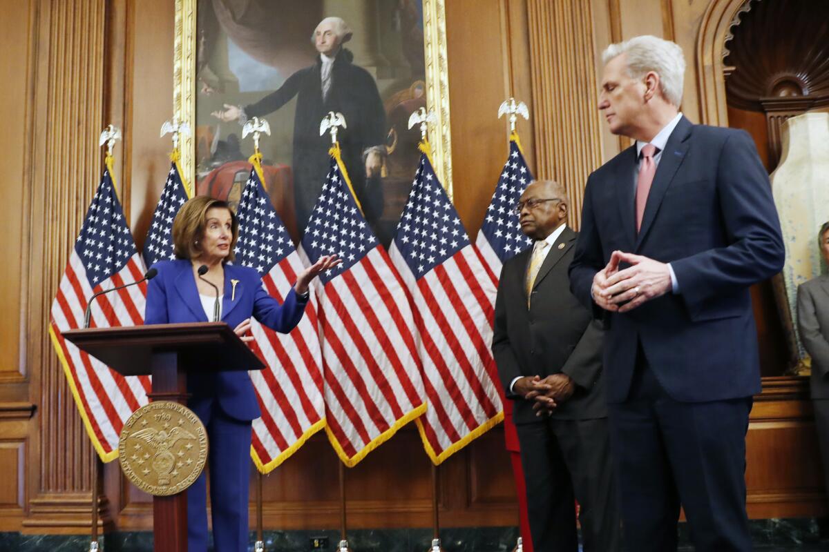 Nancy Pelosi, speaking in front of a lectern backed by U.S. flags, points at Kevin McCarthy