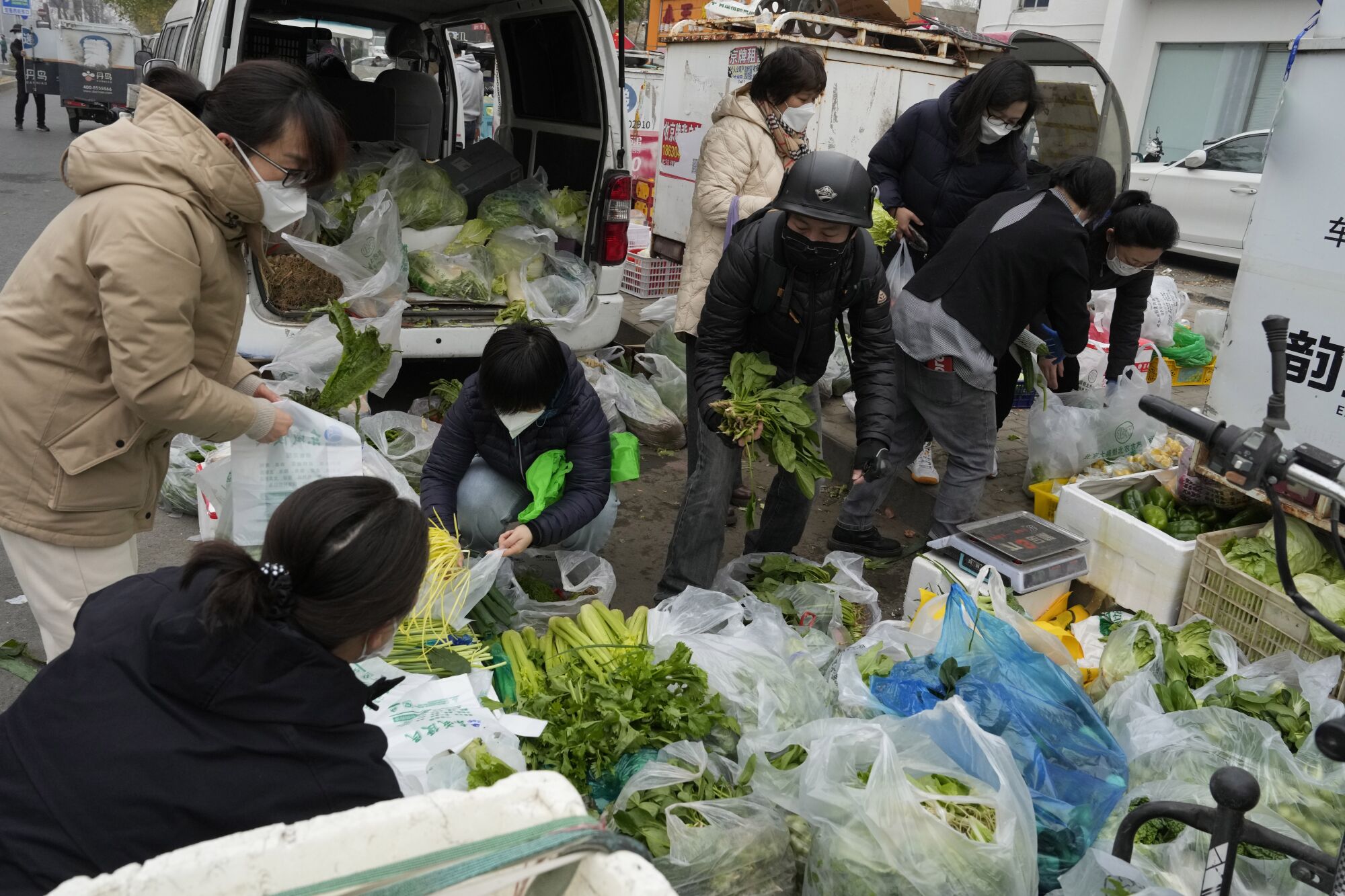 Pekin'de sokak satıcılarından sebze alan insanlar