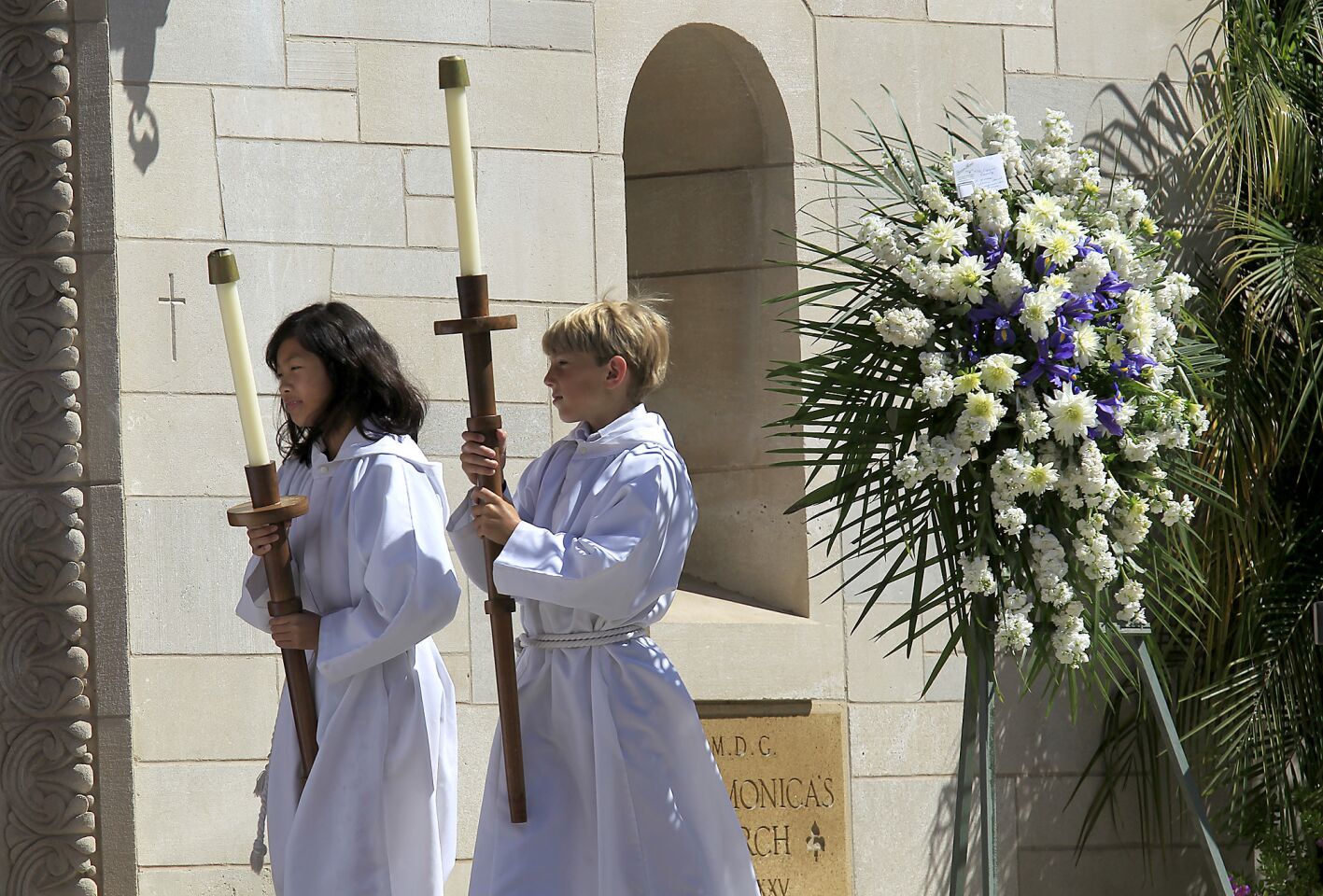 An altar girl and boy walk into St. Monica Catholic Church.