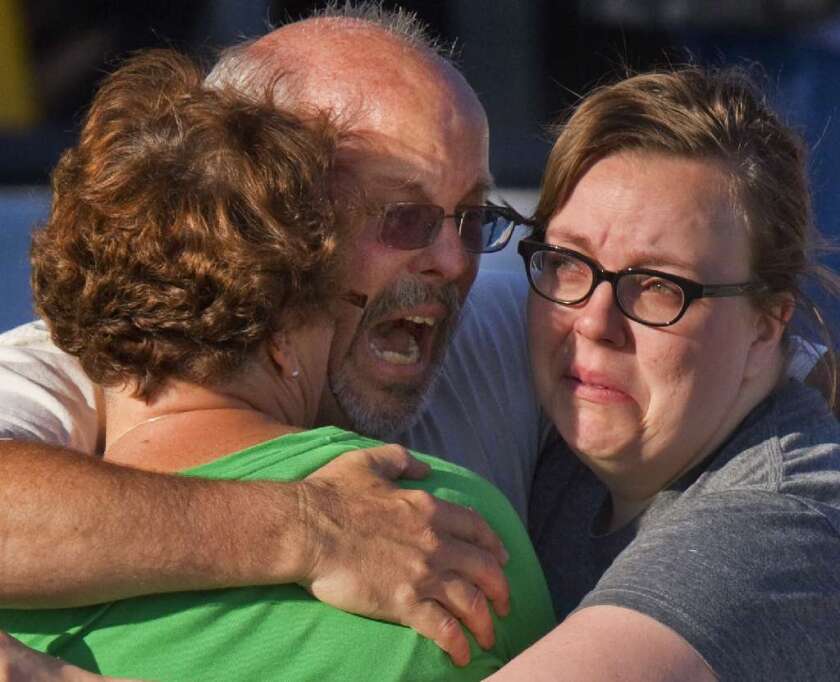 Tom Sullivan, center, embraces family members after his son, Alex, who celebrated his 27th birthday by going to see "The Dark Knight Rises," was among those killed in the Colorado movie theater shooting.
