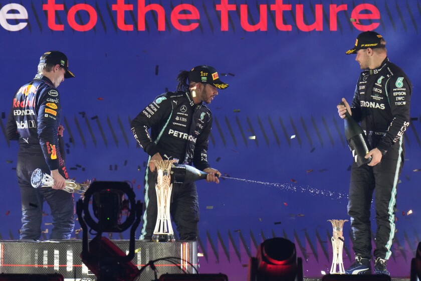 Mercedes driver Lewis Hamilton of Britain celebrates at the podium after winning the Formula One Saudi Arabian Grand Prix in Jiddah, Sunday, Dec. 5, 2021. Left is second placed Red Bull driver Max Verstappen of the Netherlands and Ron the right is third, Mercedes driver Valtteri Bottas of Finland. (AP Photo/Hassan Ammar)