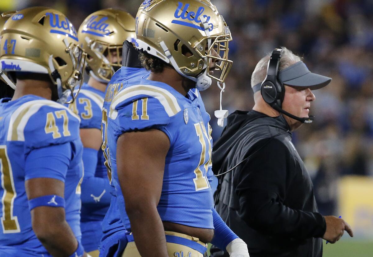 Chip Kelly on the sideline next to UCLA players.