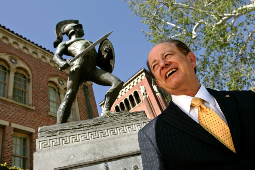 USC president C.L. Max Nikias beside a Trojan statue