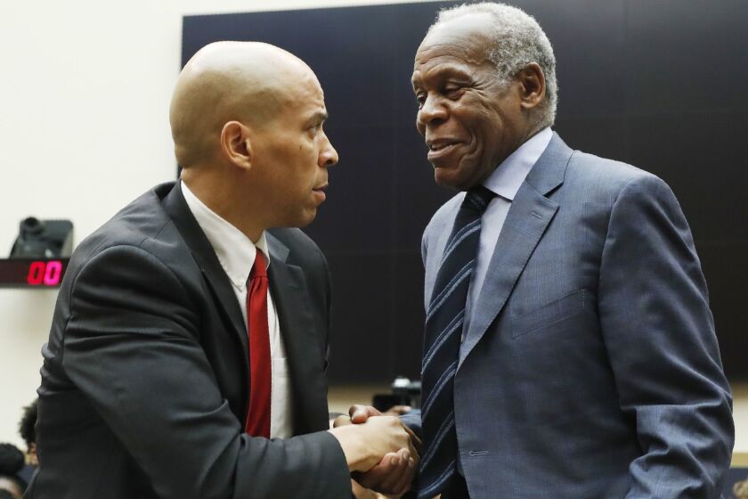 Democratic Presidential candidate Sen. Cory Booker, D-NJ, left, greets Actor Danny Glover, before they testify about reparations for the descendants of slaves, during a hearing before the House Judiciary Subcommittee on the Constitution, Civil Rights and Civil Liberties, at the Capitol in Washington, Wednesday, June 19, 2019. (AP Photo/Pablo Martinez Monsivais)