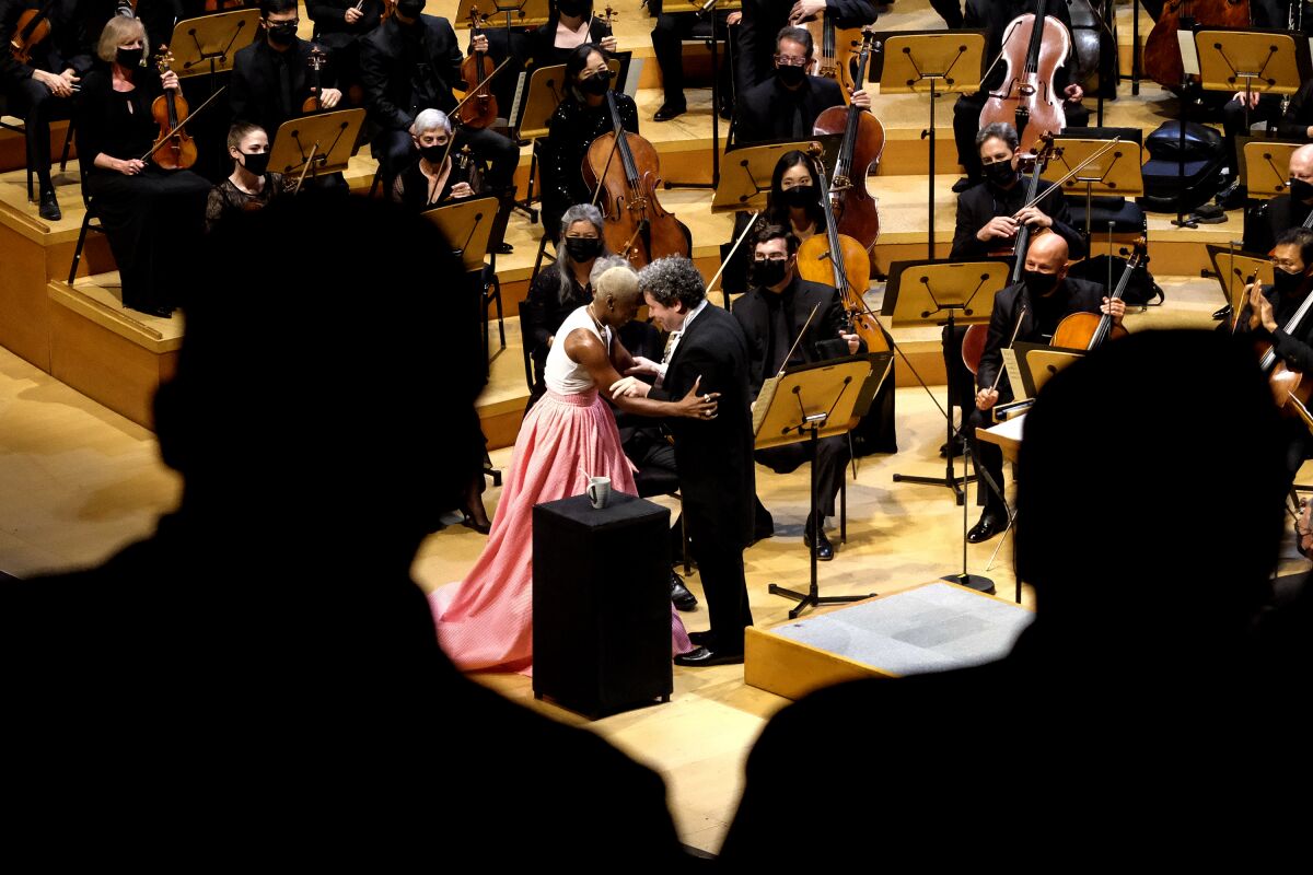 Cynthia Erivo and Gustavo Dudamel are seen through a crowd, embracing on stage.