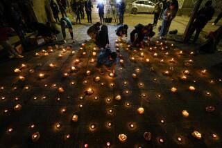 Varias personas encienden velas durante una vigilia frente a la sede de los Carabineros en honor de tres policías asesinados en el sur de Chile, el sábado 27 de abril de 2024, en Santiago. (AP Foto/Esteban Félix)