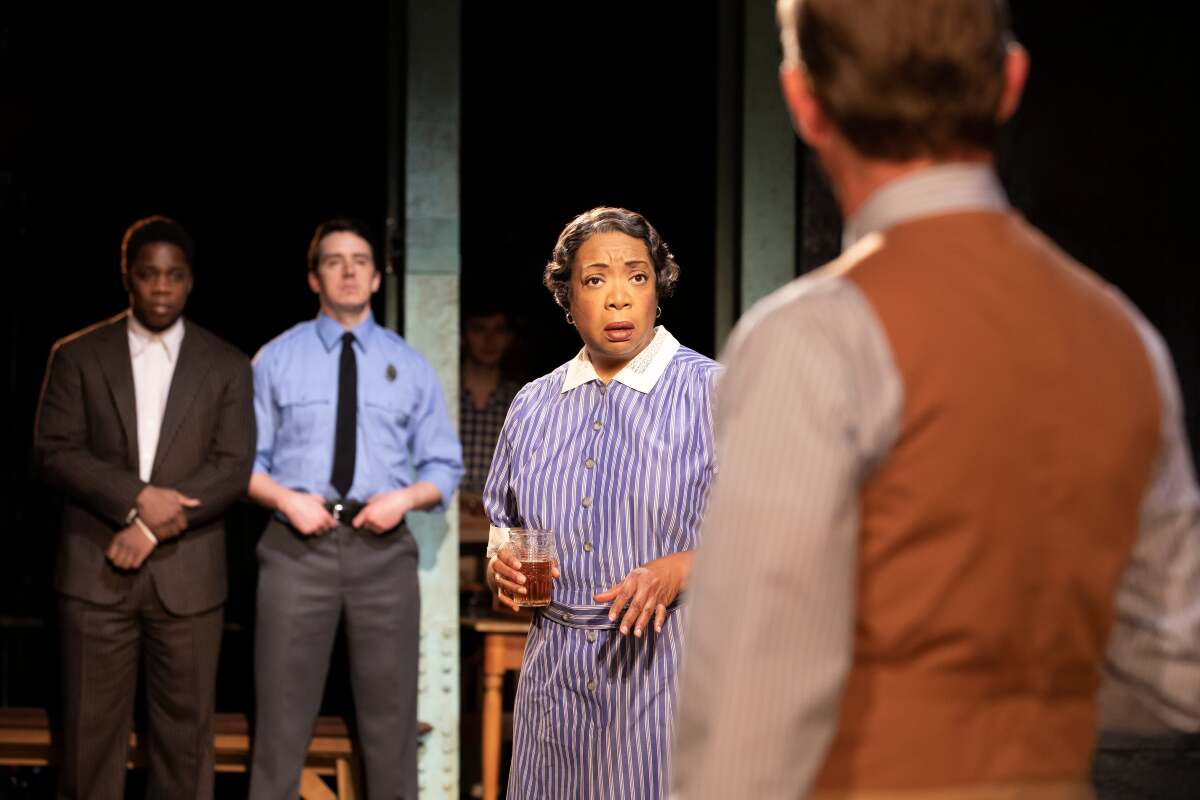 A Black housekeeper talks with her white employer as two men look on.