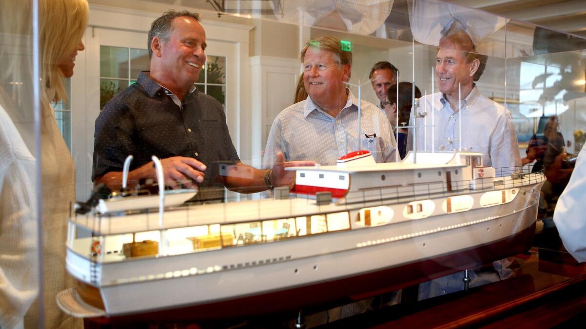 Ethan Wayne, center left, and Newport Beach Mayor Marshall Duffield, second from right, chat about the model of Wild Goose, the yacht that belonged to Wayne’s late father, John, at the Lido House hotel on Wednesday.