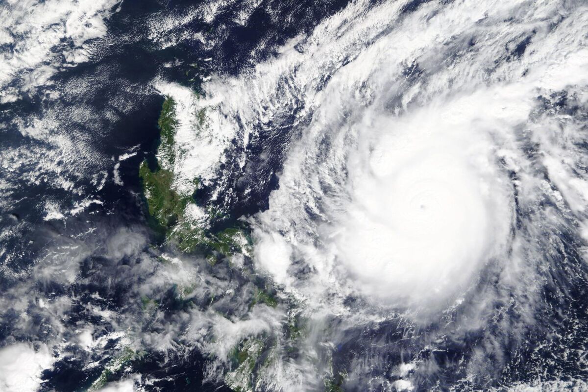 A satellite image shows the white swirl of Typhoon Goni over the ocean.