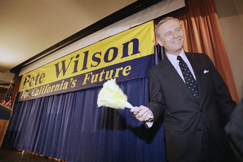 California Gov. Pete Wilson smiles after being handed a feathered duster following a news conference in Los Angeles, Nov. 9, 1994. Wilson captured re-election in Tuesday's election. (AP Photo/Bob Galbraith)