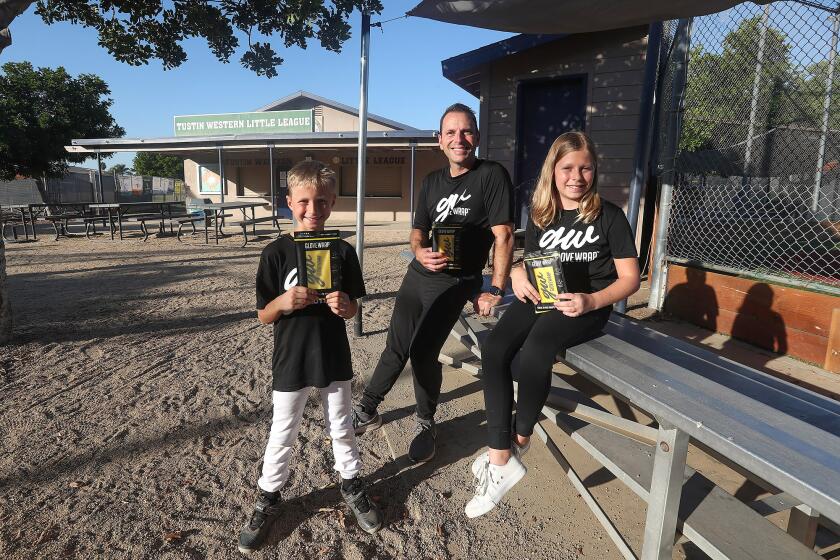 Gavin, Jon, and Morgan Batarse, from left, hold their Glove Wrap, a product to shape and break-in baseball gloves, at the Tustin Western LL baseball fields in Tustin. The family will appear on Shark Tank with their idea.