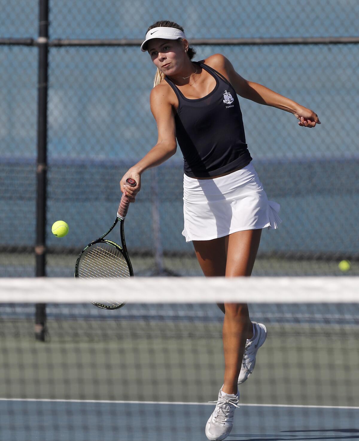 Newport Harbor's Talia Baia returns a shot against Laguna Beach during a No. 1 doubles set in a Sunset Conference crossover home match on Tuesday.