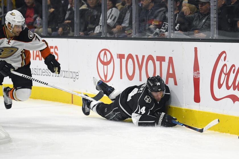 Kings defenseman Tom Gilbert, right, falls as he reaches for the puck while under pressure from Ducks left wing Andrew Cogliano during the first period Tuesday night.