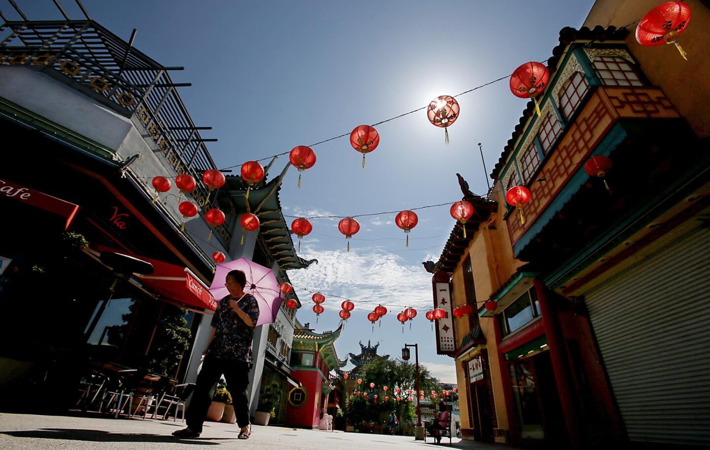 A woman uses an umbrella to shield herself from the scorching sun in L.A.'s Old Chinatown, where the mercury quickly soared into the mid-90s Friday morning.